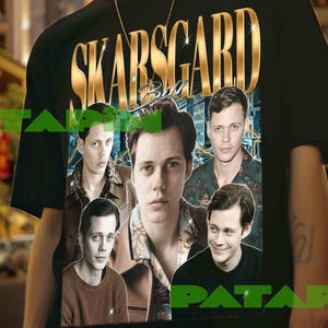 May include: Black t-shirt featuring the word "SKARSGARD" in gold lettering above a collage of images. The t-shirt is worn by a person with a gold chain necklace and a bracelet.