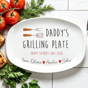 Könnte beinhalten: Weiße ovale Platte mit dem Text "DADDY'S GRILLING PLATE" und "HAPPY FATHER'S DAY 2026". Enthält eine Gabel, Tomaten, Petersilie und gegrilltes Essen. Die Platte hat eine Spatel- und Gabelgrafik.