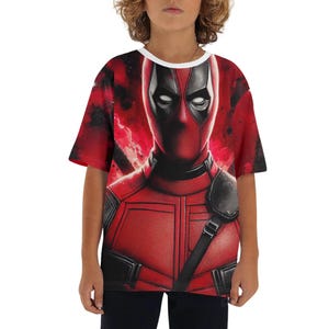 Pode incluir: Camiseta gráfica vermelha e preta com o personagem Deadpool. A camisa tem gola redonda branca e mangas curtas. O design mostra o rosto e a fantasia de Deadpool em um fundo vermelho.