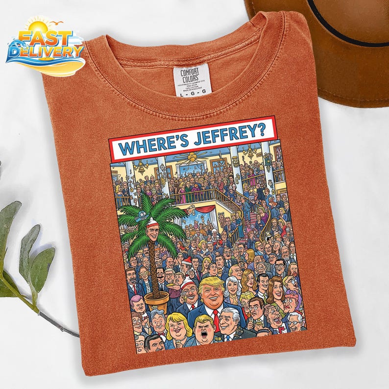 May include: Burnt orange Comfort Colors t-shirt with a graphic that reads "WHERE'S JEFFREY?" The graphic is a cartoon of a large crowd of people. A palm tree with a face is in the center of the graphic.