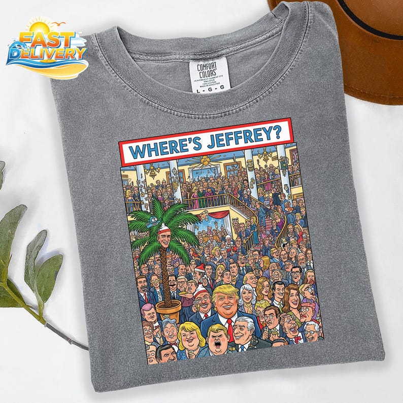 May include: Gray Comfort Colors t-shirt with a colorful graphic. The graphic features a crowd of people and the text "WHERE'S JEFFREY?" in a red and white banner. The shirt is a size L-G-G.