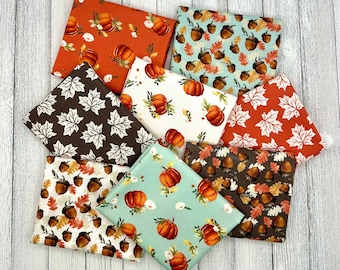 May include: Eight fabric squares with autumnal themes. The squares feature various patterns including acorns, leaves, pumpkins, and autumnal colours like brown, orange, and green.