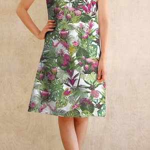May include: A white dress with a tropical print featuring green leaves, pink flowers, and a white background. The dress has a boat neck and short sleeves.