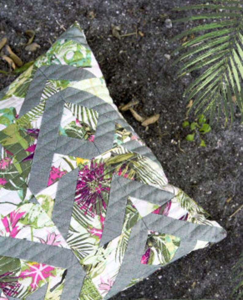May include: A square throw pillow with a gray and green geometric pattern on a white background. The pillow has a tropical floral print with pink, green, and white flowers.