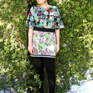 May include: A woman wearing a black and green floral print top with a matching skirt. She is wearing black leggings and black ankle boots.