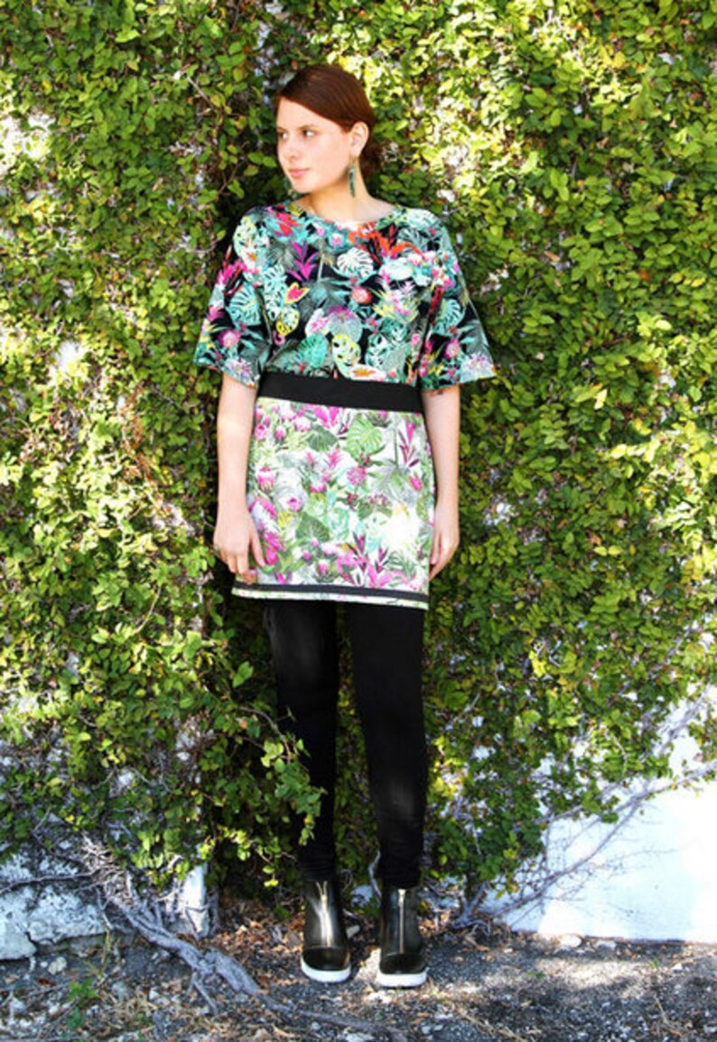 May include: A woman wearing a black and green floral print top with a matching skirt. She is wearing black leggings and black ankle boots.