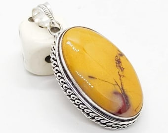 May include: Oval pendant featuring a polished, golden-yellow stone with reddish-brown veining, set in a silver-colored metal frame. The frame has a decorative rope-like border and a loop for a chain.