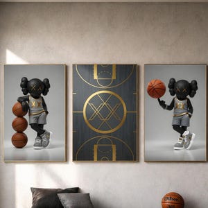 May include: A triptych of framed art featuring a basketball theme. Two panels depict a cartoon figure with basketballs, while the central panel showcases a basketball court design. A basketball sits on a leather bench in front of the artwork.