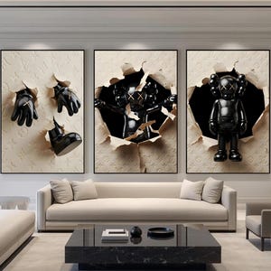 Puede incluir: Tres obras de arte enmarcadas con esculturas negras que emergen de fondos beige texturizados y rasgados. Las esculturas incluyen guantes, una bota y una figura con los ojos tachados. La obra de arte se exhibe en un sal&oacute;n moderno.