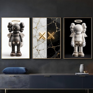 May include: Set of three framed art prints. One features a dark figure with angel wings and a halo. Another has a split design of white marble and black marble with gold accents. The third print shows a white figure with angel wings and a halo.