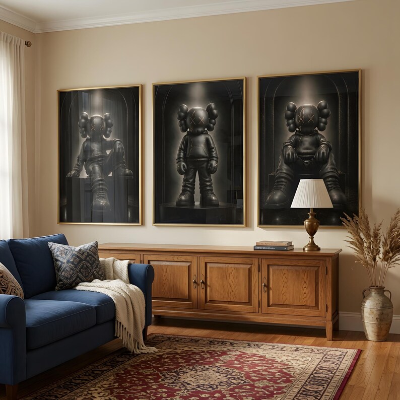 May include: Three framed wall art prints featuring black KAWS-style figures with X-shaped eyes. The figures are depicted in different poses against a dark, arched background. Each print is encased in a thin gold frame, displayed in a horizontal row.