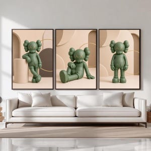 May include: A set of three framed wall art prints featuring a matte olive green cartoon character with X-shaped eyes. Each print displays the character in a different pose against a neutral beige background with geometric shapes and thin gold rings.