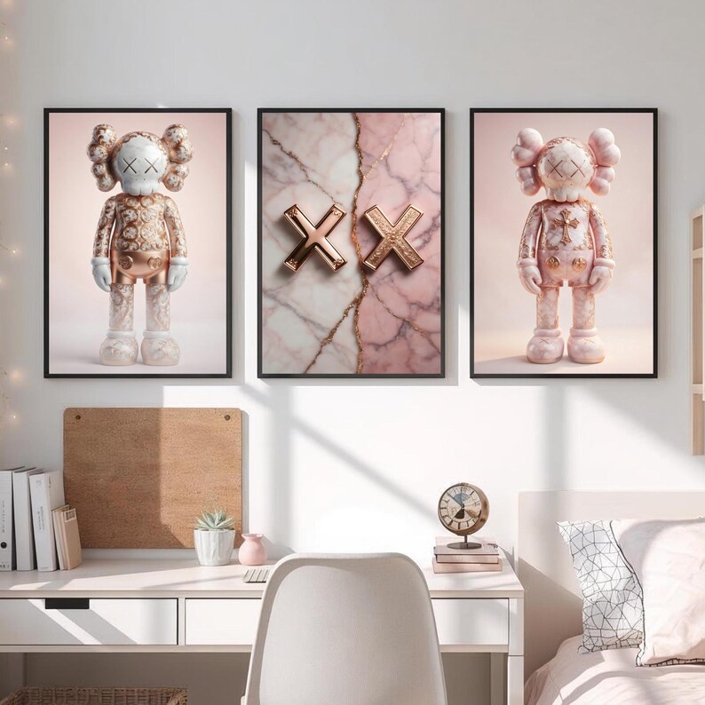 K&ouml;nnte beinhalten: Drei gerahmte Kunstdrucke. Zwei Drucke zeigen eine Figur im KAWS-Stil in Gold und Wei&szlig;. Der mittlere Druck zeigt zwei goldene "XX"-Symbole auf einem rosa-wei&szlig;en Marmorhintergrund. Alle Drucke sind in schwarzen Rahmen.