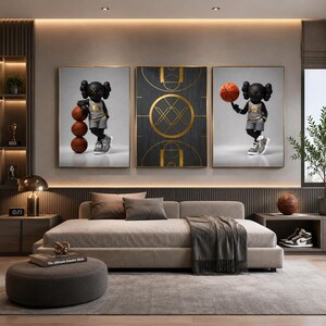 May include: Three framed art pieces featuring a black figure with crossed-out eyes, dressed in a basketball uniform, and holding basketballs. The middle piece depicts a gold and black basketball court design. The art is displayed above a modern sofa.
