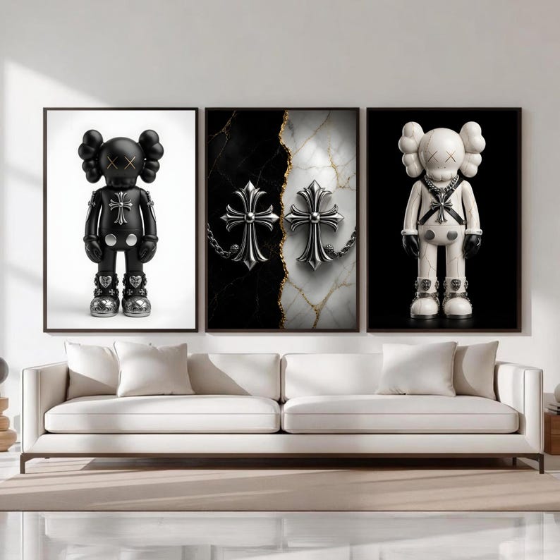 May include: A triptych of framed art pieces featuring a black and white KAWS figure and a pair of silver crosses on a marble background. The KAWS figures have X-shaped eyes. The art is displayed above a white sofa.