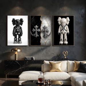 May include: Three framed art pieces. The left and right frames feature cartoon-like figures with cross-shaped accents. The center frame displays two silver crosses on a black and white marble background. The artwork is displayed above a black cabinet.
