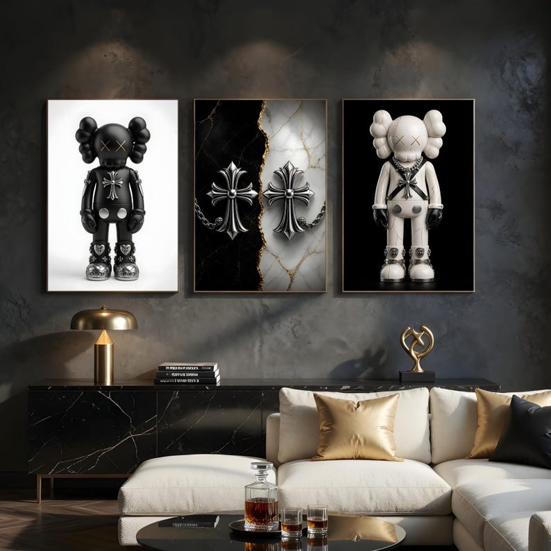 May include: Three framed art pieces. The left and right frames feature cartoon-like figures with cross-shaped accents. The center frame displays two silver crosses on a black and white marble background. The artwork is displayed above a black cabinet.
