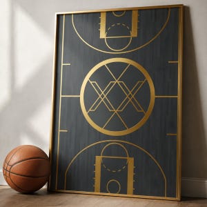 May include: A framed basketball court art print with a gold-colored frame. The print features a dark gray background with gold-colored lines depicting a basketball court design. A brown basketball rests on the floor next to the print.