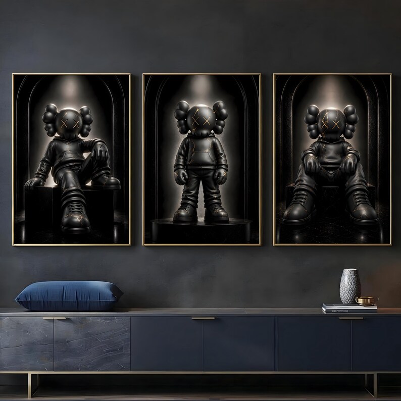 May include: A set of three framed wall art prints featuring black cartoon-style figures with X-shaped eyes. Each figure wears a hooded sweatshirt and trainers, positioned within a dark, arched alcove setting with subtle gold-toned accents.
