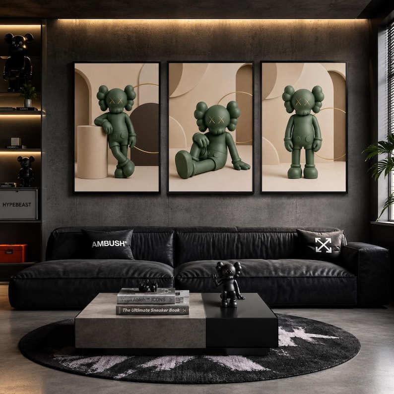 May include: A set of three framed wall art prints featuring a matte olive green cartoon character with X-shaped eyes. Each print displays the character in a different pose against a neutral beige background with geometric shapes and circular lines.