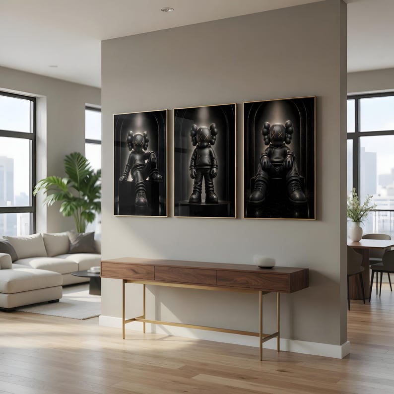 May include: A set of three framed wall art prints featuring black cartoon-style figures with X-shaped eyes. Each print displays a different pose of the same character against a dark, arched background with a spotlight effect, mounted on a wall.
