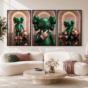 Puede incluir: Un tr&iacute;ptico de impresiones de arte mural enmarcadas que presenta un personaje verde esmeralda brillante con ojos en forma de X y detalles en oro rosa. El personaje se muestra en tres poses dentro de un pasillo arqueado, de pie, gesticulando y sentado.