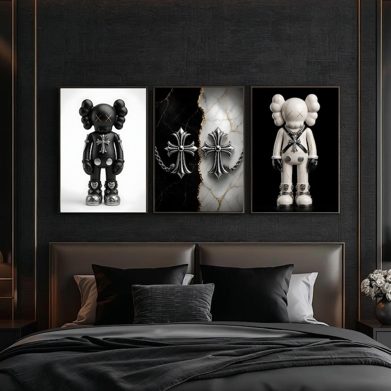 May include: Three framed art pieces featuring a black and white color scheme. One shows a black figure with silver accents, another has two silver crosses on a marble background, and the last displays a white figure with black accents. The art is displayed above a bed.