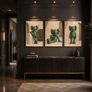 May include: A set of three framed wall art prints featuring a green cartoon character with X-shaped eyes in different poses. The character is depicted against a neutral beige background with geometric shapes, displayed above a dark sideboard.