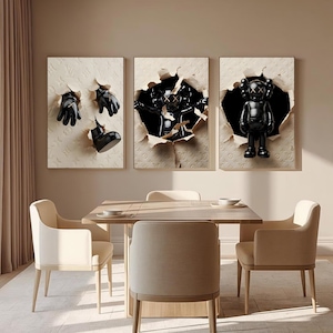 Puede incluir: Un tr&iacute;ptico de obras de arte enmarcadas con esculturas negras que emergen de papel rasgado. Las obras de arte incluyen un par de guantes, una bota y una figura KAWS. El fondo tiene un patr&oacute;n repetitivo. La obra de arte se exhibe sobre una mesa de comedor con sillas.