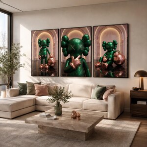 Puede incluir: Un conjunto de tres l&aacute;minas de arte mural enmarcadas que muestran un personaje verde brillante con ojos en forma de X. El personaje aparece en varias posturas, de pie y sentado, junto a una esfera de color oro rosa met&aacute;lico en un pasillo.