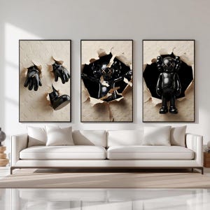 Puede incluir: Un tr&iacute;ptico de obras de arte enmarcadas con objetos negros que emergen de fondos beige texturizados rasgados. El arte incluye guantes negros, una bota y una figura negra con los ojos tachados. Los marcos son negros, sobre un sof&aacute; blanco.