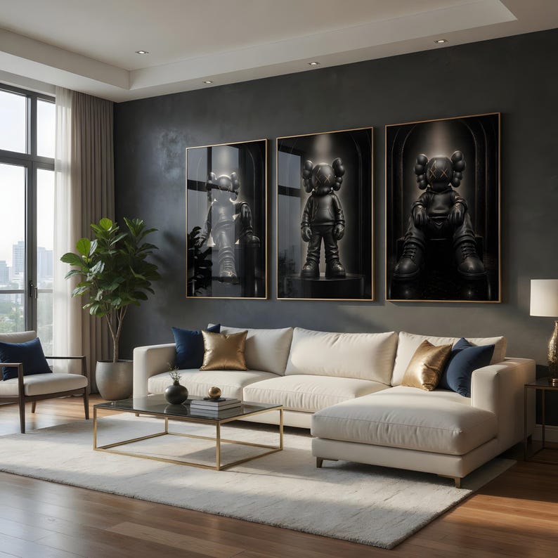 May include: Three framed vertical wall art prints featuring black monochromatic figures with X-shaped eyes, displayed in a row above a cream-coloured sectional sofa with navy blue and gold throw pillows, a glass coffee table, and a potted plant.