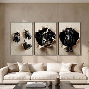 Puede incluir: Un tr&iacute;ptico de obras de arte enmarcadas con figuras y accesorios negros que emergen de papel rasgado. La obra de arte incluye una figura negra con ojos en X, guantes y una bota. El fondo es un patr&oacute;n beige.