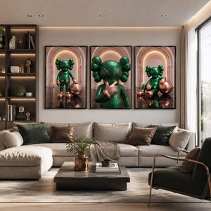 Puede incluir: Un conjunto de tres cuadros de pared con impresiones enmarcadas de un personaje verde brillante con ojos en forma de X. El personaje aparece en varias posturas, de pie y sentado, junto a una esfera de cobre met&aacute;lico en un arco.