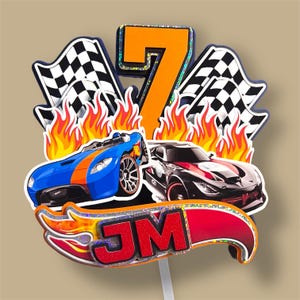 Puede incluir: Un adorno para pastel colorido con dos coches de carreras, llamas, banderas a cuadros y el número 7. El adorno incluye las iniciales "JM" en un diseño de llama, perfecto para una fiesta de cumpleaños.