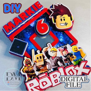 May include: A colorful Roblox-themed cake topper with the name "Markie" and the number "6" in red. The design includes Roblox characters and the text "DIGITAL FILE". The background features a starry sky.