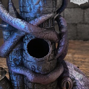 May include: A dark purple and blue stone tower sculpture wrapped in thick, textured tentacles. The structure features a circular opening in the center and a large, reptilian eye at the base. A logo in the corner reads FATES END 2026 YEAR OF THE HORSE.