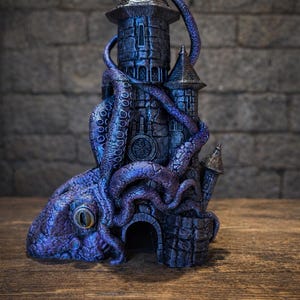 May include: A dark purple and blue 3D printed tower sculpture featuring a large octopus with a prominent eye wrapped around the stone-textured structure. The top of the tower displays a logo with a unicorn and the text FATES END YEAR OF THE HORSE 2026.