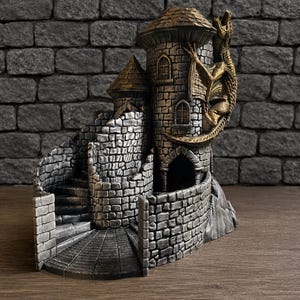 Könnte beinhalten: Ein detailliertes Miniatur-Schloss mit einer Drachenskulptur. Das Schloss weist steinartige Texturen, eine Wendeltreppe und mehrere Türme auf. Der Drache ist goldfarben und umschlingt den Hauptturm, was dem Design ein Fantasy-Element hinzufügt.