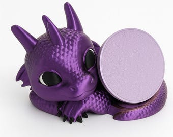 May include: A metallic purple dragon figurine with large black eyes and textured scales. The dragon is in a resting position with its head tilted, featuring a smooth, light purple circular disc attached to its side for holding small items.