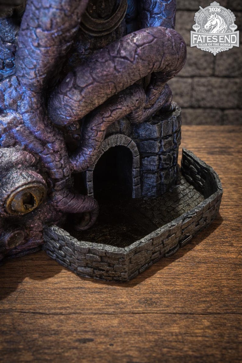 May include: A purple and blue textured dice tower featuring a large eye and winding tentacles wrapped around a stone structure with an arched doorway and a low brick wall enclosure. A logo in the corner reads FATES END 2026 YEAR OF THE HORSE.