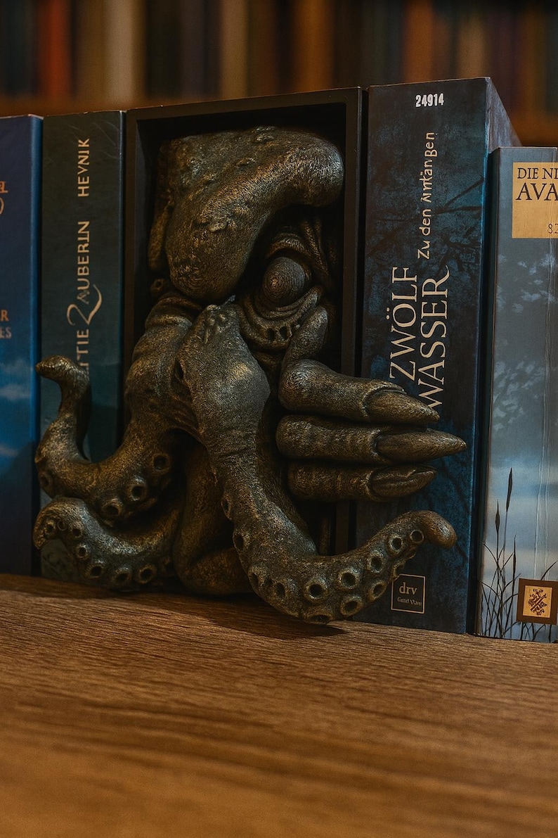 May include: A bronze-colored octopus bookend with detailed tentacles and a textured surface. The bookend is placed between two books with text on the spines, including "ZW&Ouml;LF WASSER" and "TIE ZAUBERIN HEYNIK".