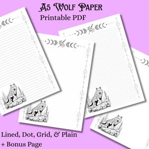 May include: A5 Wolf Paper printable PDF with lined, dot, grid, and plain pages. Each page features a detailed black and white illustration of a wolf and forest scene. The pages have a decorative border with crescent moon and dot designs.
