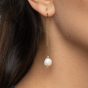 May include: Gold chain earrings with a single white pearl dangling at the end.