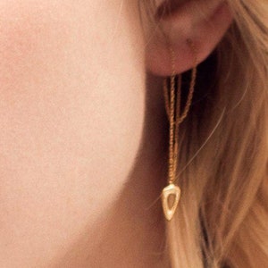 Könnte beinhalten: Nahaufnahme eines Frauen Gesichts mit blonden Haaren. Sie trägt einen goldenen Anhänger-Ohrring in Tropfenform.