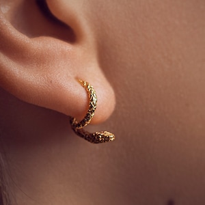 Female model wearing snake ear jacket earrings in polished 24K gold-plated finish.