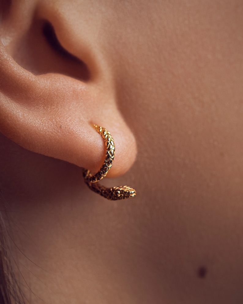 Female model wearing snake ear jacket earrings in polished 24K gold-plated finish.