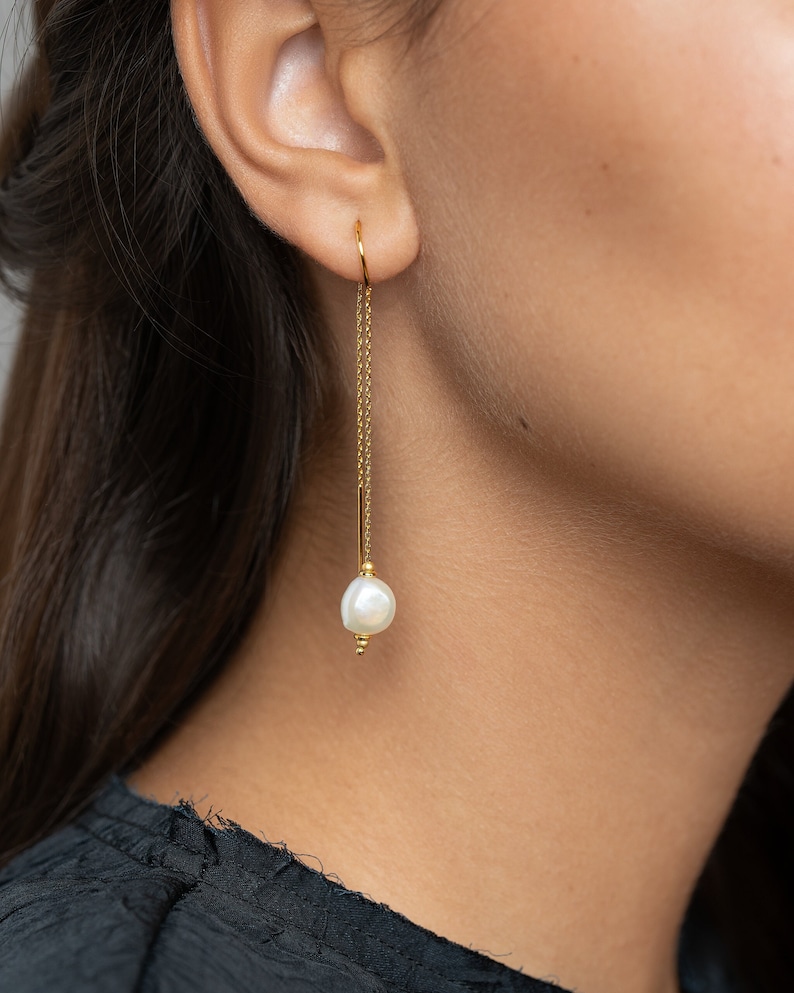 May include: Gold chain earrings with a single white pearl dangling at the end.