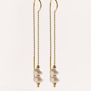 May include: A pair of gold chain earrings with two white pearl drops at the end of each chain.