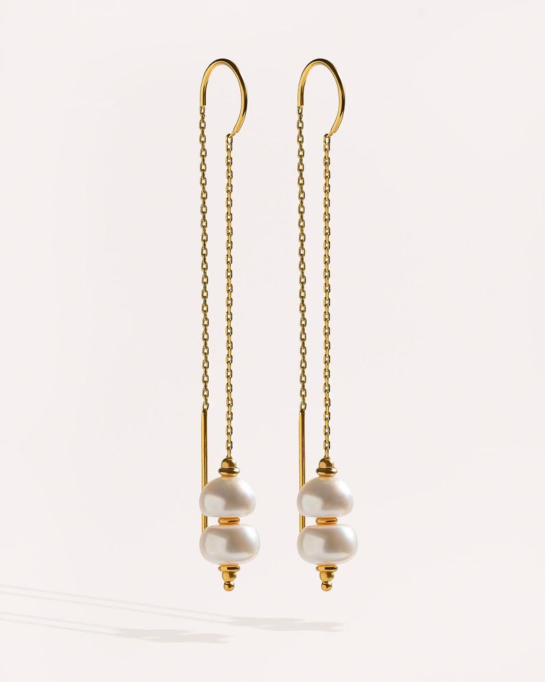 May include: A pair of gold chain earrings with two white pearl drops at the end of each chain.